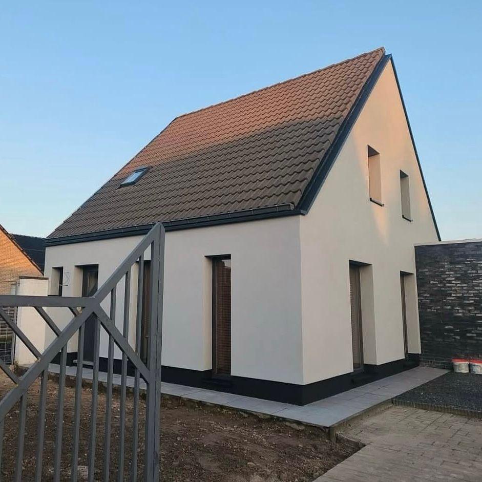 Woning met crème gekleurde crepi gevel en donkere dakrand na gevelwerken door De Renovatie Meesters